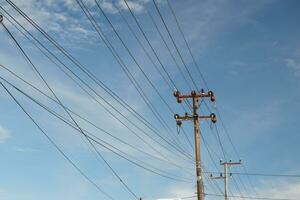 Electric cable poles against a bright blue sky photo