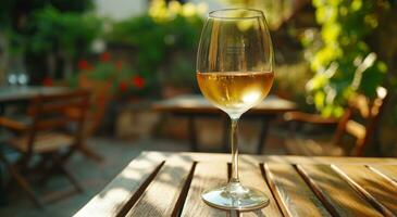 ai generado un vaso de blanco vino es tendido en un mesa al aire libre foto