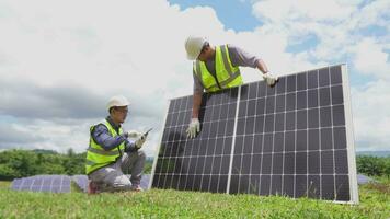 une équipe de deux ingénieurs sont travail à installer solaire panneaux à une solaire Puissance gare. ingénieur équipe discuter le travail à installer solaire cellules. techniciens inspecter et réparation solaire cellules. video