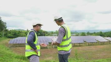 dos ingenieros son trabajando a Instalar en pc solar paneles a un solar poder estacion.tecnicos inspeccionar y reparar solar células. video