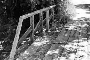 Beautifully standing old wooden bridge over river in light background photo