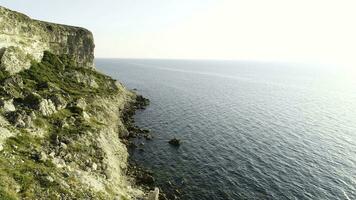 Spectacular view of steep dliffs at the ocean, Ireland. Shot. Green slope near calm water and the endless horizon on clear blue sky background. photo