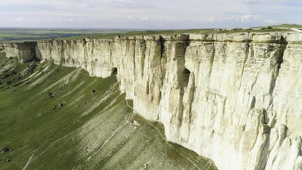 Stunning landscape of White Rock in Crimea with bright green meadow at the foot. Shot. Aerial for the beautiful mountain with flat top and green field on cloudy sky background. photo