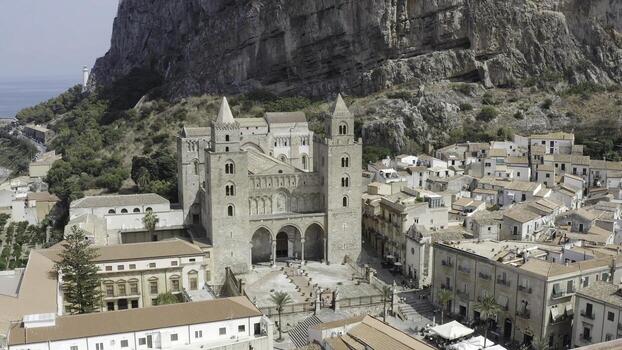 Amazing view of the grey old cathedral surrounded by buildings with large mountain cliff on the background in warm summer day. Action. Gorgeous ancient architecture photo
