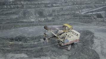 Top view of excavator in open pit. Excavator falls asleep rubble in dumper on outdoor quarry in extraction of minerals. Concept of extraction of minerals photo