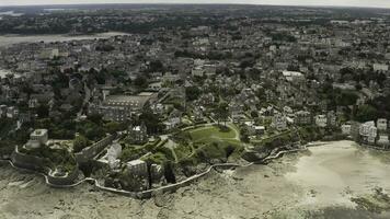 Aerial wonderful view of a city with many greenery and beautiful architecture located near the sea shore. Action. Coastal city and blue sea in a summer time. photo