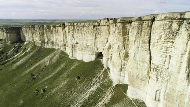 Stunning landscape of White Rock in Crimea with bright green meadow at the foot. Shot. Aerial for the beautiful mountain with flat top and green field on cloudy sky background. photo
