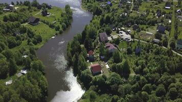 Aerial view of a town with many green trees located along the river in a sunny summer day. Clip. Ecologically clean area with small beautiful houses and narrow river. photo
