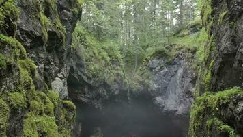 Top view of gorge between rocks in forest. Stock footage. Two cliffs covered with moss hang over small gorge with fog on background of forest. Gorge suggestive fear your mystical haze photo