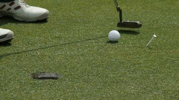 Professional golfer putting ball into the hole. Golf ball by the edge of hole with player in background on a sunny day. photo