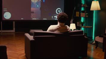 Man playing shooter videogame on TV with gun shooting laser bullets at flying robots in dark atmospheric industrial setting. Gamer enjoying competitive PvP fps internet multiplayer tournament game video