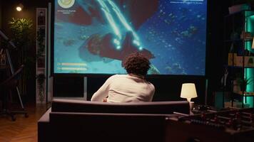 African american gamer playing classic arcade space shooter videogame on big smart TV, shooting asteroids. Zoom in shot on man using gaming console to solve missions in singleplayer game video