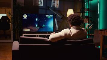 bipoc gamer giochi gioco con navicella spaziale tiro laser flussi utilizzando mirino copertura per colpire nemici. raggio tracciato grafica e alto fps scifi video gioco visualizzato su televisione impostare, Ingrandisci nel tiro