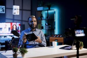 African american man filming tech tutorial on how to do maintenance on broken tablet, presenting internal parts. Technology internet show host teaching subscribers how to open and fix digital device photo