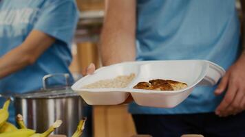 Close-up on caucasian man serving bread chicken and baked beans to poor hungry person at food drive. Detailed view of meal box from hunger relief team given to the needy. Selective-focus handheld. photo