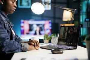 de cerca de africano americano persona de libre dedicación sentado a mesa a hogar teniendo vídeo conferencia con masculino colega. hembra Universidad estudiante estudiando en línea con computadora portátil, virtual comunicación con profesor. foto