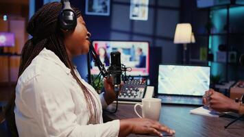 zoom in Aan influencer in studio gebruik makend van hoog tech microfoon voor online tonen Aan live streaming kanaal. vrouw aan het doen podcasting sessie met professioneel streaming geluid versnelling, dichtbij omhoog schot video