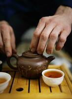 Clay teapot and several mugs of tea in a tea ceremony. Tea ceremony photo