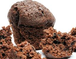 Whole and broken into pieces chocolate muffin isolated on a white background. Chocolate chip muffin. photo