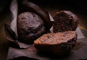 Whole and halved chocolate cupcake on a dark background. Muffin with chocolate chips on dark paper. photo