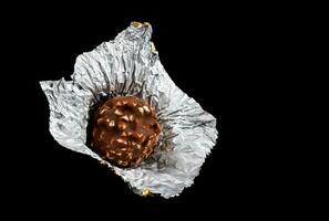 Unwrapped chocolate candy in foil on a black background. photo