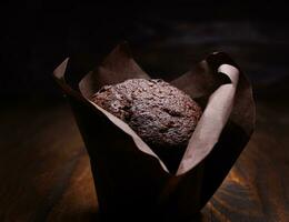 Chocolate cupcake on a dark background. Muffin with chocolate chips on a wooden surface. photo