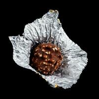 Unwrapped chocolate candy in foil on a black background. photo