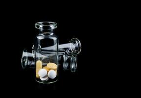 Glass transparent bottles with pills inside. Pills isolated on a black background. photo