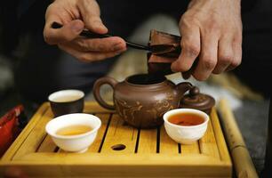 Clay teapot and several mugs of tea in a tea ceremony. Tea ceremony photo