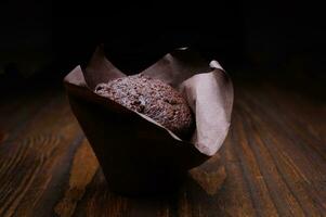 Chocolate cupcake on a dark background. Muffin with chocolate chips on a wooden surface. photo