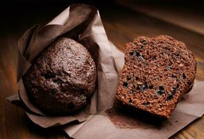 Whole and halved chocolate cupcake on a dark background. Muffin with chocolate chips on dark paper. photo