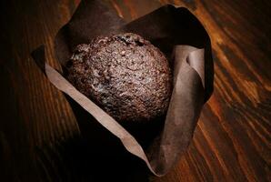 Chocolate cupcake on a dark background. Muffin with chocolate chips on a wooden surface. photo