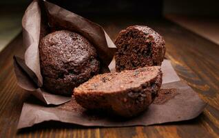 todo y reducido a la mitad chocolate magdalena en un oscuro antecedentes. mollete con chocolate papas fritas en oscuro papel. foto