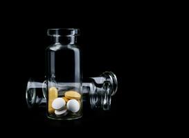 Glass transparent bottles with pills inside. Pills isolated on a black background. photo