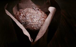 Chocolate cupcake on a dark background. Muffin with chocolate chips on a wooden surface. photo