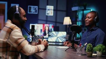 African american influencer recording podcast with man, talking in studio. Zoom in shot of cheerful man listening to guest live during broadcasting session for internet show video