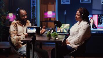 Radio show presenter using professional camera to record live conversation with man in personal studio. Influencer talking with woman, sharing interesting facts for fans at home video