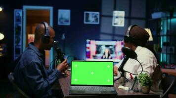 Focus on green screen laptop in front of show host recording podcast, using analog mixer in studio. Mockup notebook and man setting up audio devices in live broadcast for flawless sound quality video