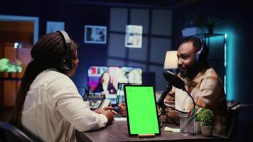 Isolated screen tablet next to cohosts streaming podcast using professional vlogging gadgets on vlog channel. Chroma key device between podcasters meeting in studio to film show video