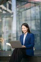 Confident Asian woman with a smile standing holding notepad and tablet at out side office photo