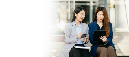 Businesswoman and woman going in city center in smart casual business style, talking, working together, stylish freelance people, holding tablet photo