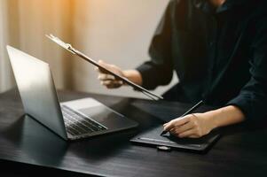 business documents on office desk with laptop and smart phone and graph business diagram and man working in office photo