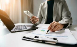 business documents on office desk with laptop and smart phone and graph business diagram and man working in office photo