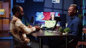 African american man invited to podcast, welcomed by friendly host, participating in entertaining discussion in studio. Cheerful guest fist bumping and saluting online comedy show presenter video