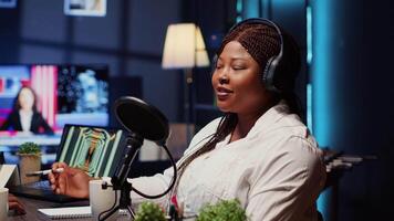 Guest on online podcast show telling interesting story to host, captivating viewers watching during live broadcast. African american woman in studio sharing facts, surrounded by audio tech video