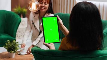 Woman tourist looking at tablet with greenscreen display in hotel lobby, checking isolated mockup template on modern wireless gadget. Guest with chromakey on device in lounge area. video