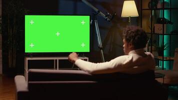 Mens gebruik makend van geïsoleerd scherm slim TV naar kijk maar nieuws programma omroep in leven kamer. koord snijder aan het kijken chroma sleutel ultrawide televisie Scherm tonen vod kanaal, ontspannende Aan bankstel video