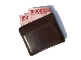 Brown wallet and one hundred thousand Indonesian money. Indonesian rupiah wallet and money on a white background. photo