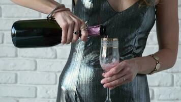 alcohol drinks concept. woman in cocktail dress pouring rose champagne into glass flute, white brick wall background video