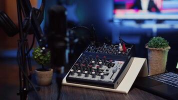 Close up shot of analog mixer and microphone used to produce impeccable sound quality during podcast recording in dimly lit studio. Cutting edge audio recording equipment on table in apartment video